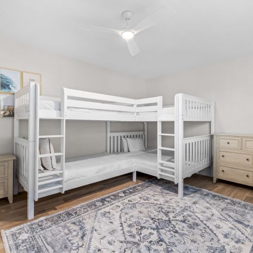 Room with white bunk beds and blue rug