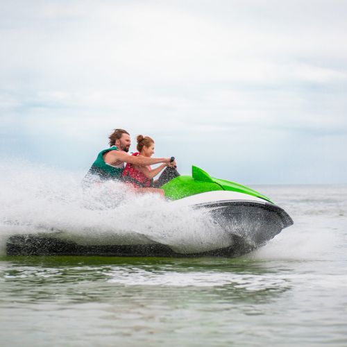 young people having fun driving on high speed on water scooter, man and woman on summer vacation, friends doing active sport