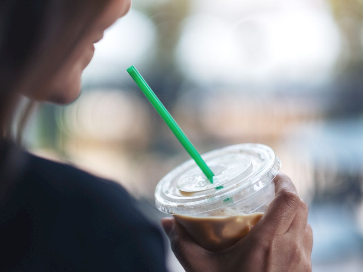 A beautiful woman holding a plastic glass of iced coffee