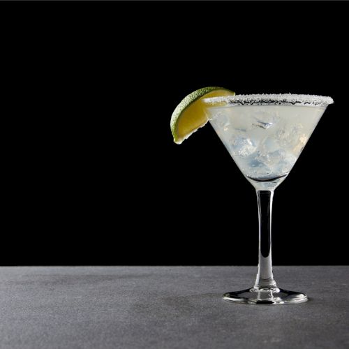 close up view of tasty margarita cocktail with lime and ice on tabletop on black