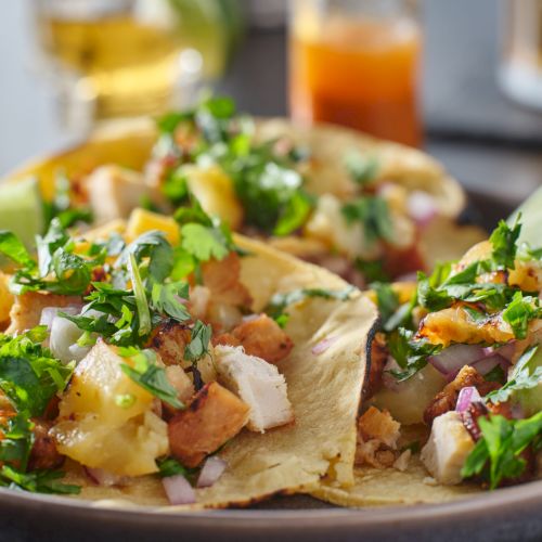 colorful grilled pineapple and chicken street tacos on plate with lime