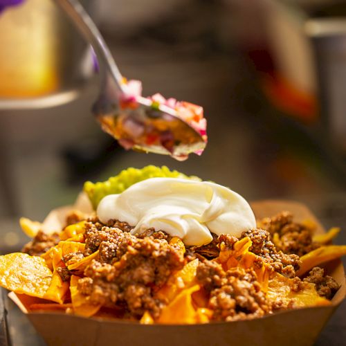 Mexican street fast food with tacos, fajitas and nachos. Chef preparing food in truck, adding salsa.