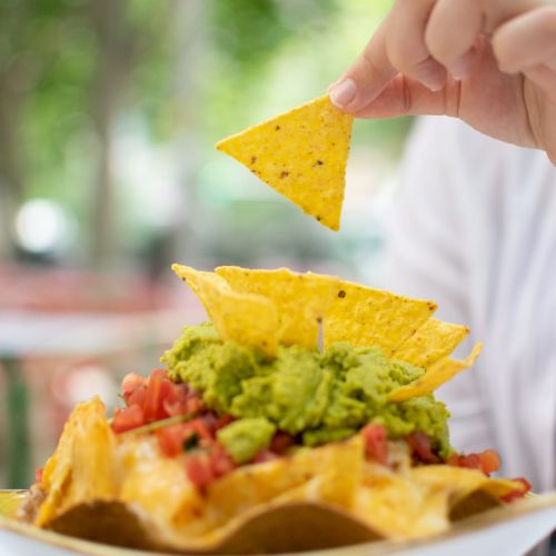 Plate of nachos topped with guacamole and salsa