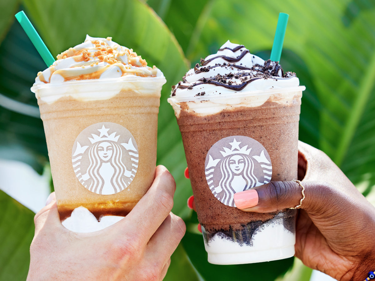 Three Starbucks frappuccinos held up against green leaves