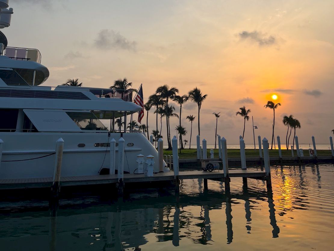 Yacht docked at sunset with palm trees in the background