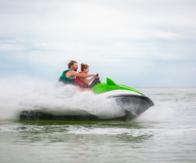 young people having fun driving on high speed on water scooter, man and woman on summer vacation, friends doing active sport