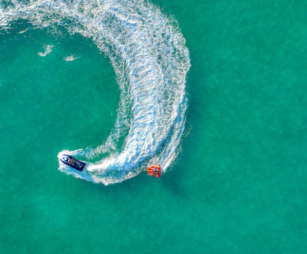 Aerial view of a boat towing a tube on turquoise water