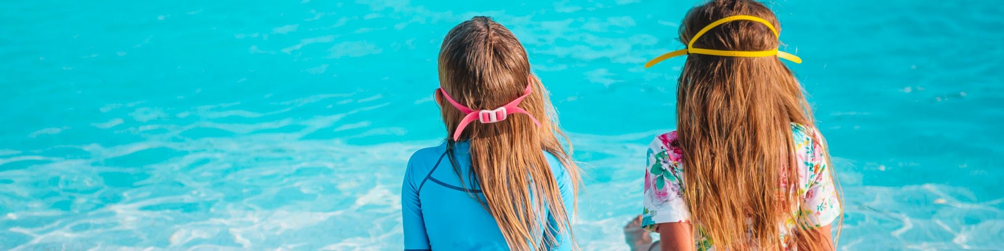 Adorable little girls playing in outdoor swimming pool on vacation