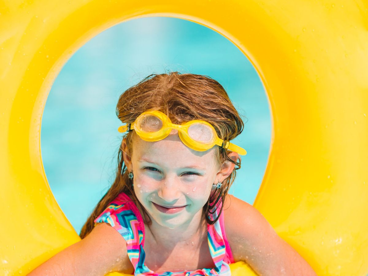 Little girl swims in outdoor swimming pool with inflatable rubber ring