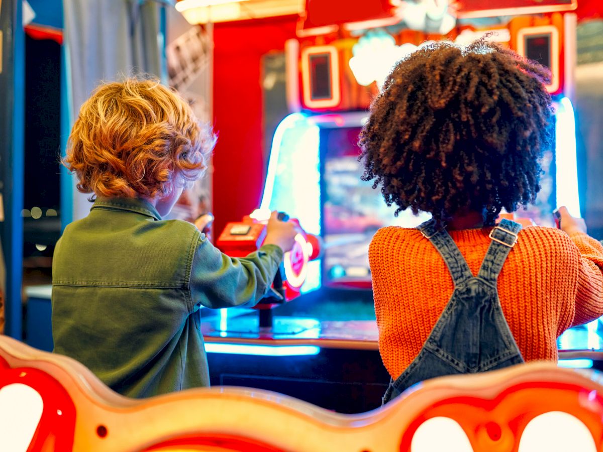 Two kids playing shooting games at an arcade