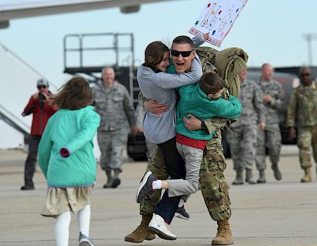 A joyful military homecoming with family hugs