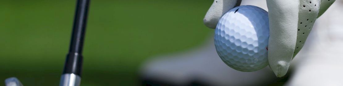Golfer placing ball on tee with club ready