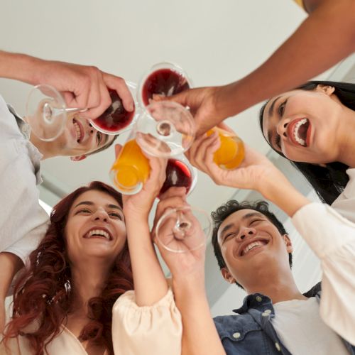 Excited happy friends clinking with glasses when celebrating birthday at home