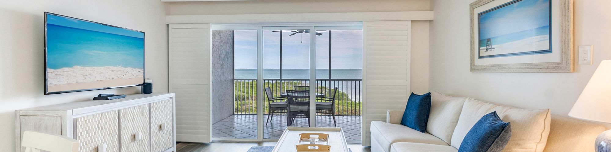 Bright living room with ocean view, blue accents, and sliding glass doors
