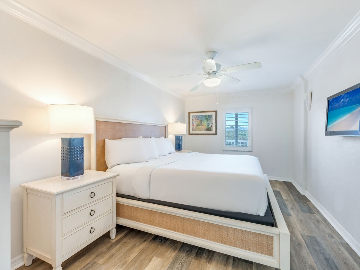 Bedroom with king bed, white walls, and blue lamps.