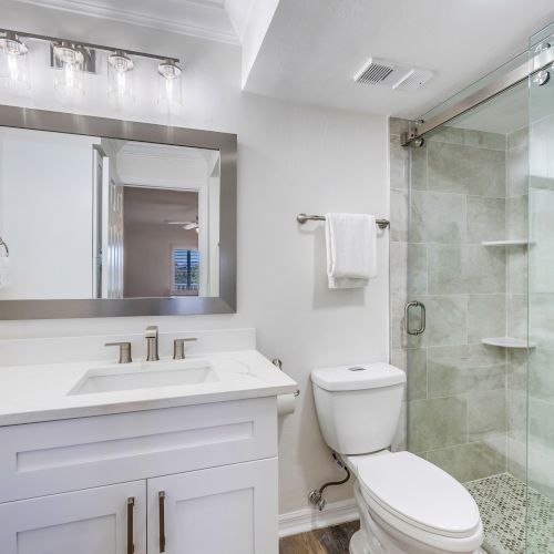 Modern bathroom with glass shower and white vanity.