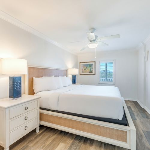 Bedroom with king bed, white walls, and blue lamps.