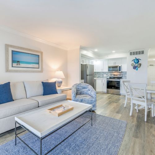 Living room and kitchen with coastal decor, blue accents, and wood flooring.