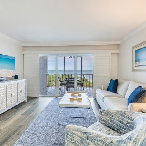 Bright living room with ocean view, blue accents, and sliding glass doors