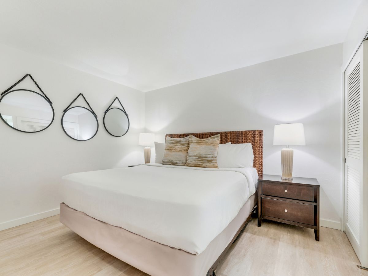 Bed with two pillows, two lamps on nightstands, and three round mirrors on the wall