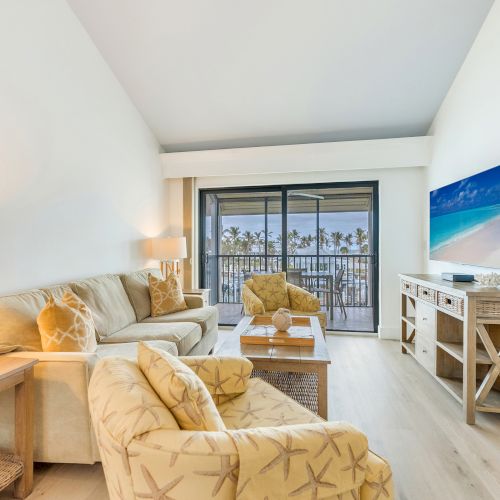 Living room with sofa chairs TV and balcony view