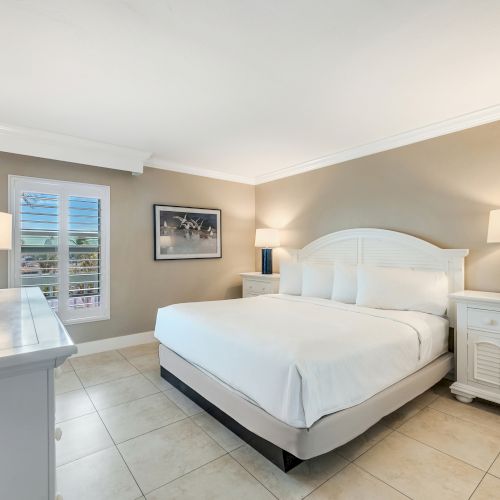 Bedroom with a white bed, two nightstands and a wall mounted TV.