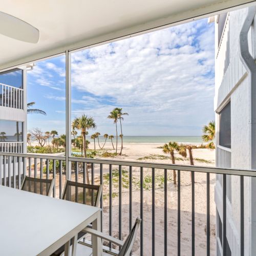 Balcony with table, chairs, and beach view.