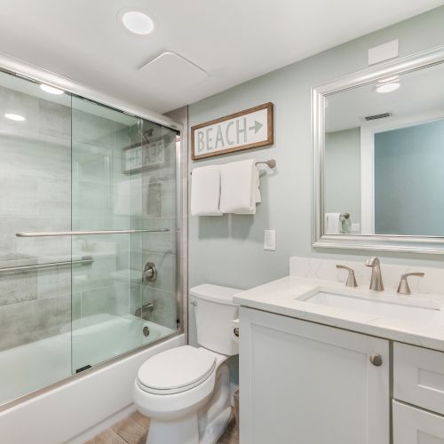 Bathroom with glass shower, toilet, and sink.