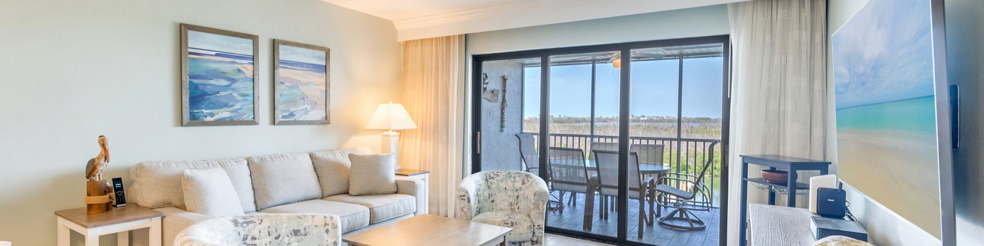 Living room with plush seating, wood floors, and a balcony view of the ocean.