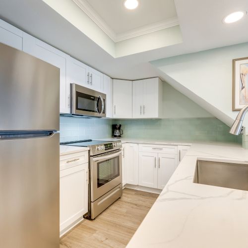 Modern kitchen with stainless steel appliances, white cabinets, and a light blue backsplash