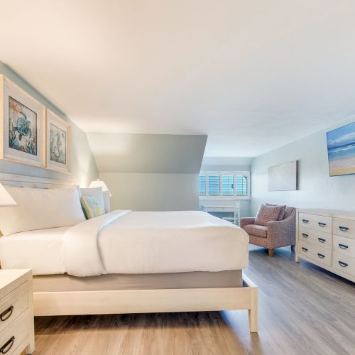 Bedroom with a king size bed, lounge area, and soft beachy color palette