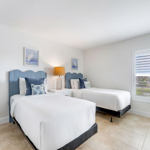 Bedroom with two beds and blue headboards.