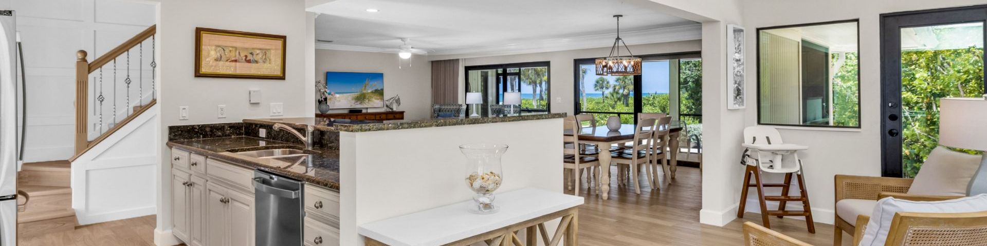 Kitchen with granite counters, dining area, and large windows overlooking greenery
