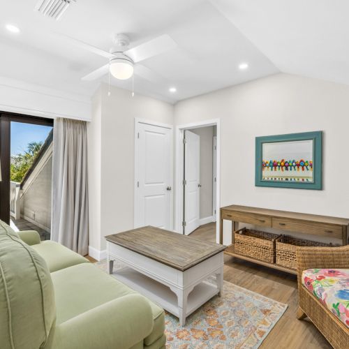 Small sitting room with green sofa, coffee table, and ceiling fan