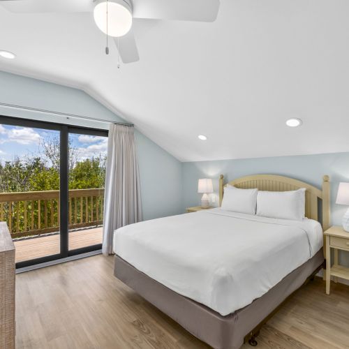Bedroom with white bedding, glass doors, and outdoor view