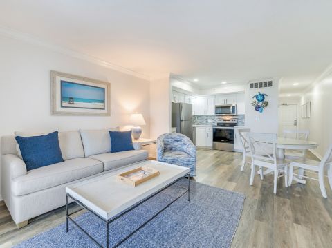 Living room and kitchen with coastal decor, blue accents, and wood flooring.