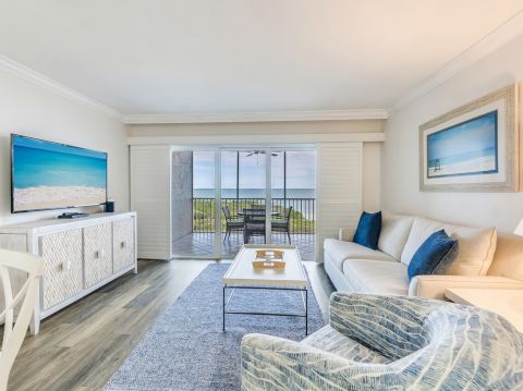 Bright living room with ocean view, blue accents, and sliding glass doors