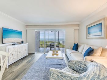 Bright living room with ocean view, blue accents, and sliding glass doors