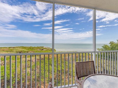 Screened balcony overlooking beach and ocean.
