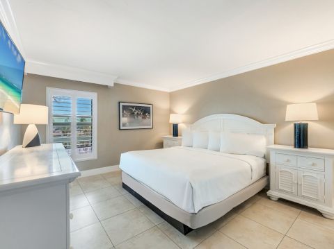 Bedroom with a white bed, two nightstands and a wall mounted TV.