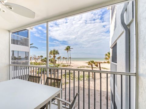 Balcony with table, chairs, and beach view.