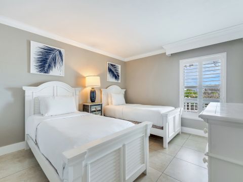 Bedroom with two white twin beds, nightstand, and window.