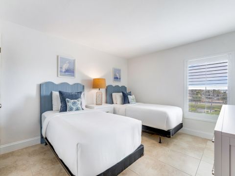 Bedroom with two beds and blue headboards.