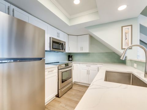 Modern kitchen with stainless steel appliances, white cabinets, and a light blue backsplash