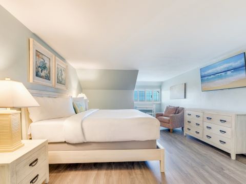 Bedroom with a king size bed, lounge area, and soft beachy color palette
