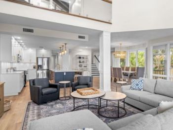 Living room with gray sectional, black chairs, and open kitchen and dining area