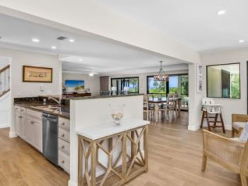 Open-concept space with kitchen, wooden floors, and dining area with large windows