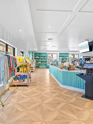 Bright modern store aisle with “Provisions” signs, shelves of goods, and a counter for checkout and food items.