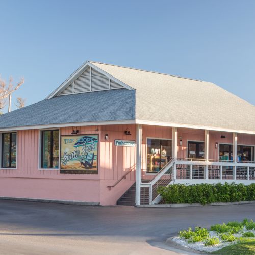 A seaside shop storefront named &ldquo;The Shops South Seas&rdquo; with a &ldquo;Provisions&rdquo; sign under a clear blue sky.