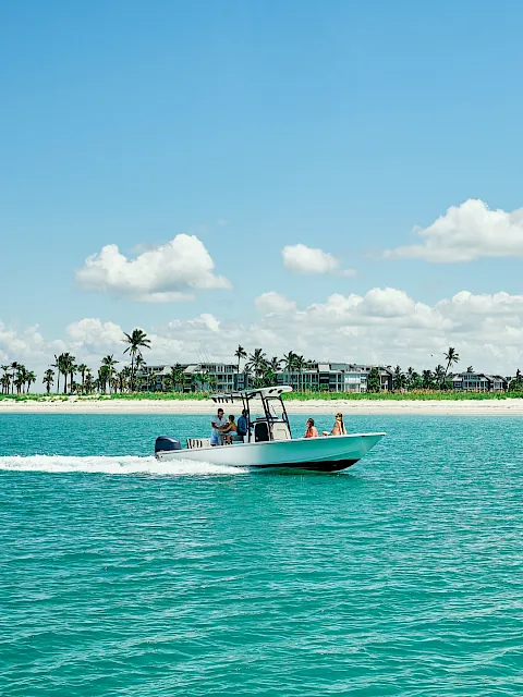 A boat cruising across turquoise water in front of the South Seas beach and palm-lined resort.